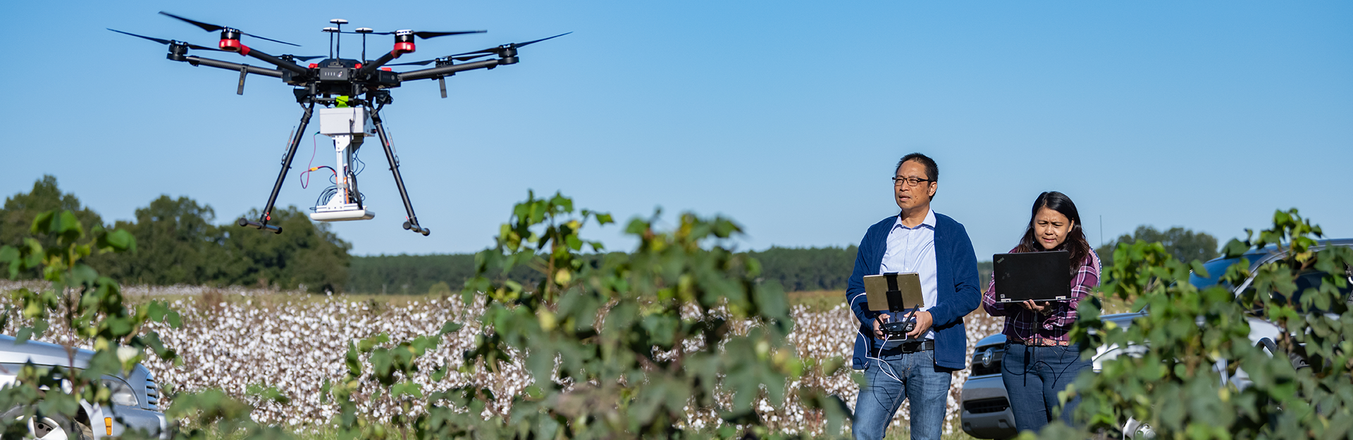 Two researchers flying a drone in a field