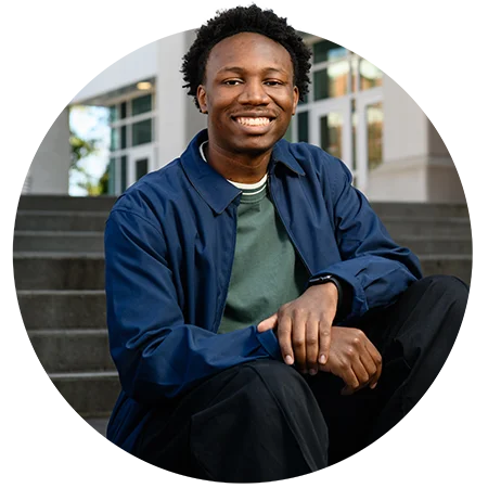 A male student poses on the steps of an academic building