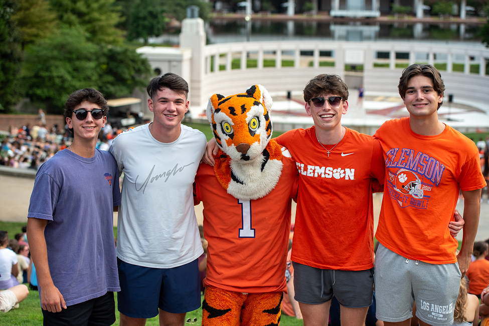 Four male students wearing shorts and T-shirts stand with the Clemson Tiger mascot.
