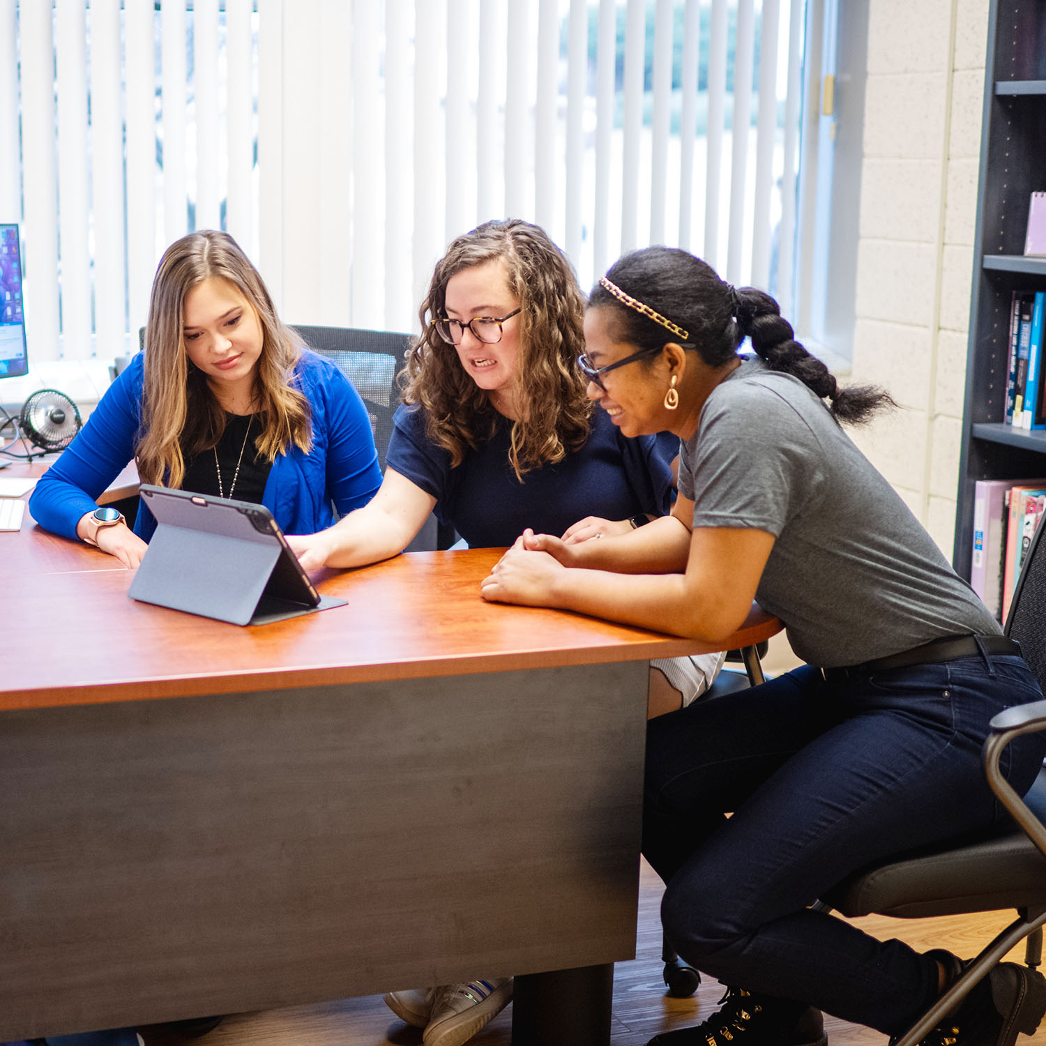 Three women looking at a tablet.