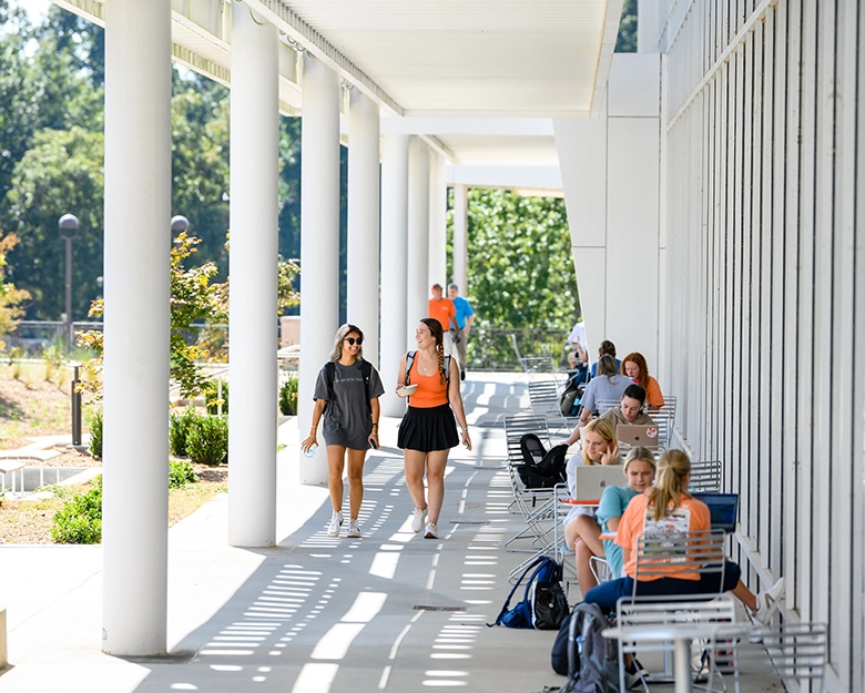 students fill the tables and walkways outside of the Watt center on a sunny spring day