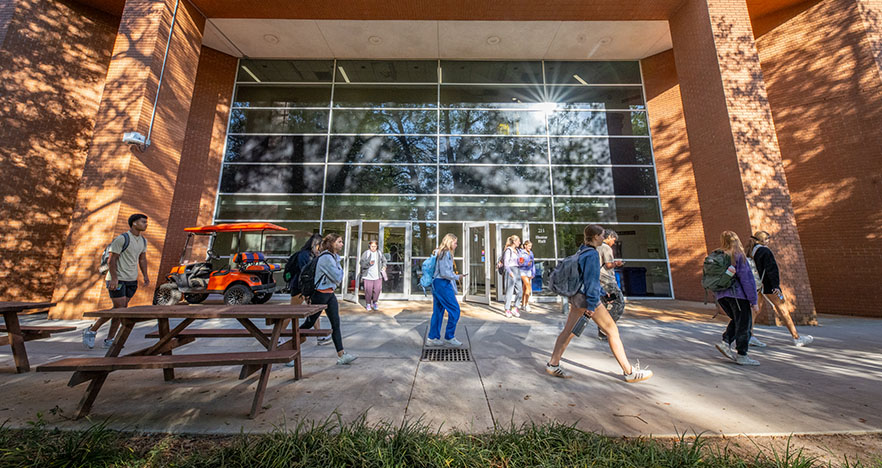 Students walk to and from classes in front of the Howard L. Hunter Chemistry Laboratory Building.