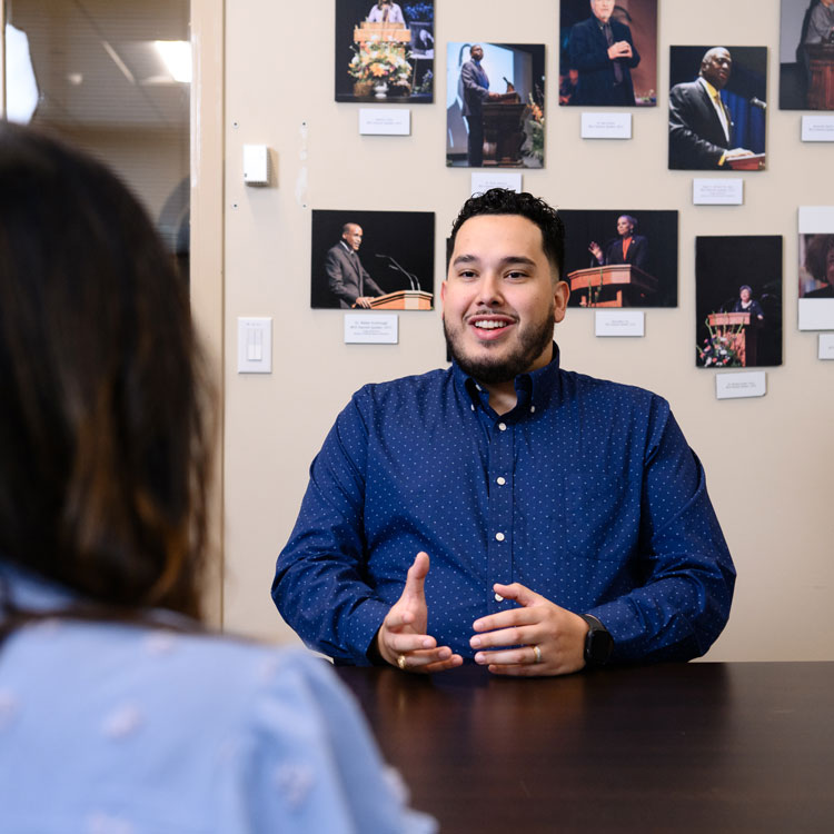 Christian Barrientos consults a student from across a desk