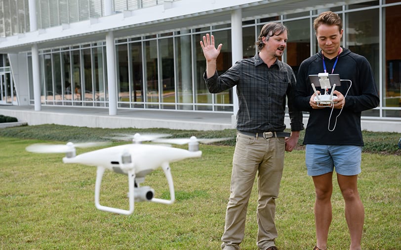 Clemson professor explains a concept as a drone hovers nearby.