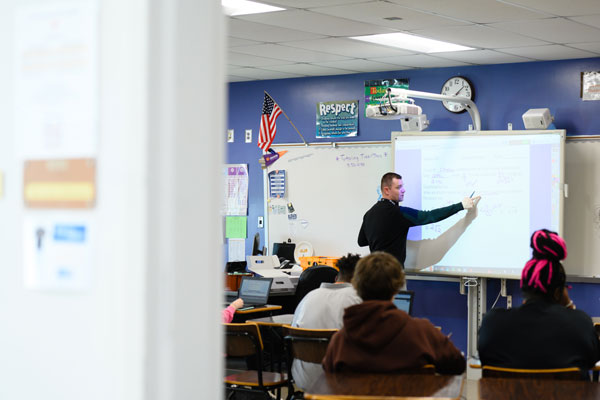 A male student resident instructs a highschool class from a smartboard