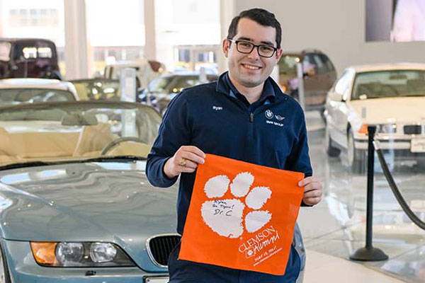 a male student with a tiger rag poses in a BMW factory showroom