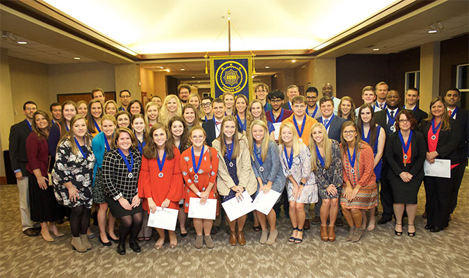 A student walks at graduation wearing a Phi Kappa Phi medal