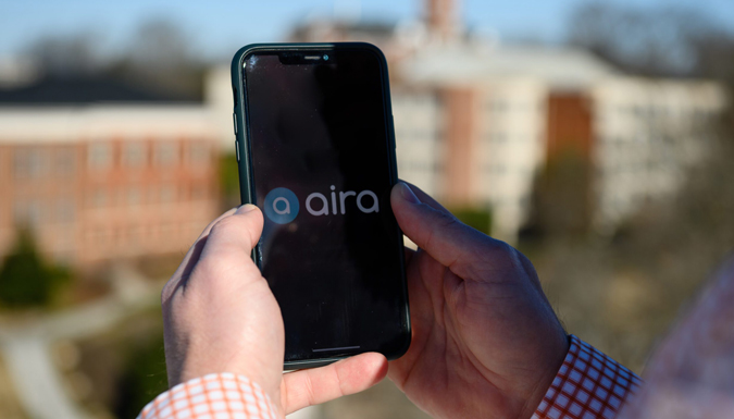 A man's hands holding an iPhone with an Aira logo