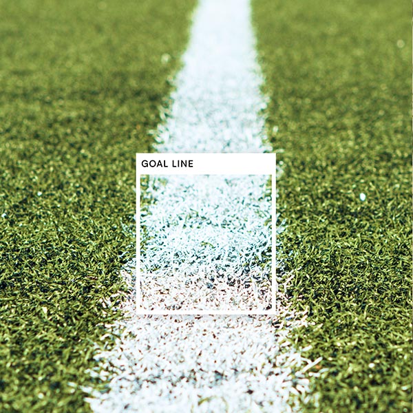 An white painted line on a football field has a square set apart noting the color Goal Line 