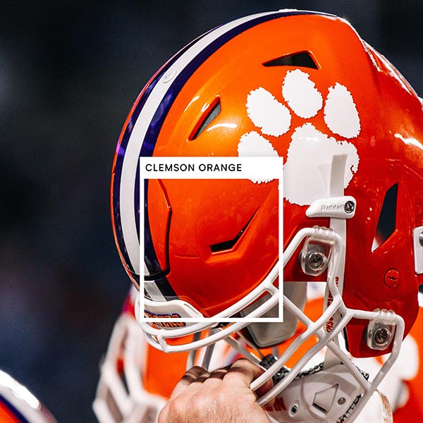 An orange Clemson football helmet has a square set apart noting the color Clemson Orange. 