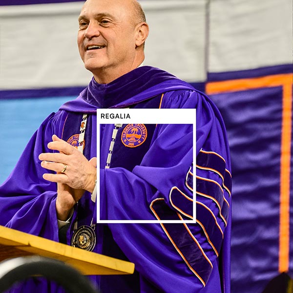 An photo of President Clements in Graduation Regalia helmet has a square set apart noting the color Regalia. 