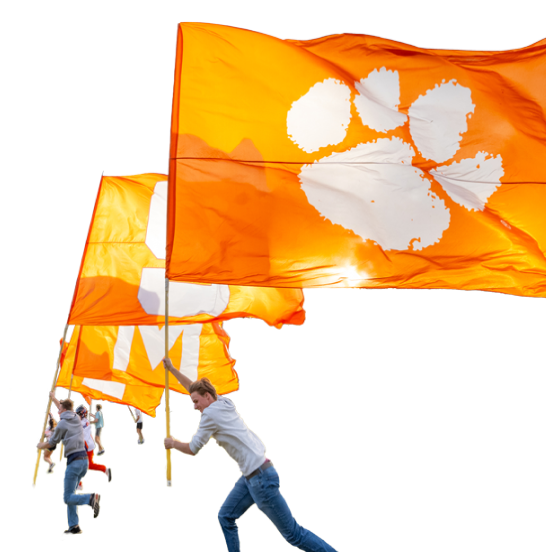 Students run with large orange and white Clemson flags. 