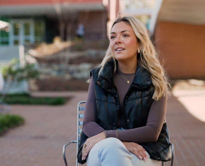 student sitting in a chair in front of the library