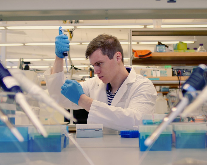 student pipetting in a lab environment