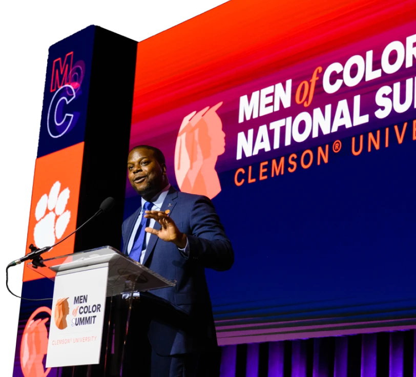 A black man stands at a podium delivering a speech at the Clemson Men of Color National Conference.