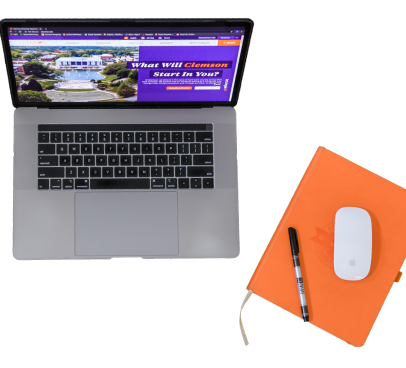 Laptop with clemson.edu homepage displayed along with a mouse and an ink pen on top of a notebook