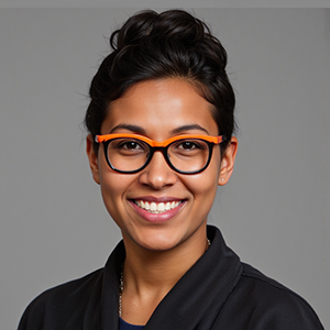 Portrait of a smiling woman with short black hair and orange-accented glasses.