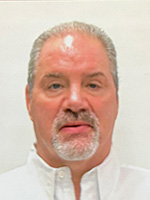 Headshot of a middle-aged man with grey hair and a goatee, wearing a white collared shirt.