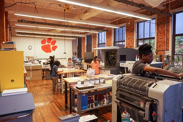 Graphics Communication students standing at booth behind table and holding tiger rag.