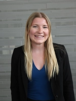 Professional portrait of a smiling woman in a business suit against a modern, light-colored background.