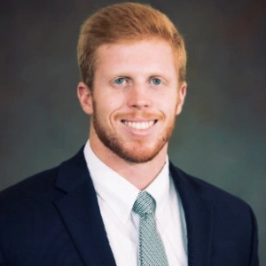 Professional headshot of a smiling man in a suit and tie.