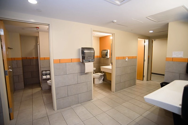 Interior view of a public restroom featuring multiple stalls, sinks, and hand dryers.