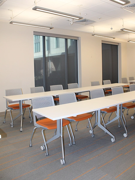 Modern conference room setup with multiple tables and ergonomic chairs, featuring bright, natural lighting.