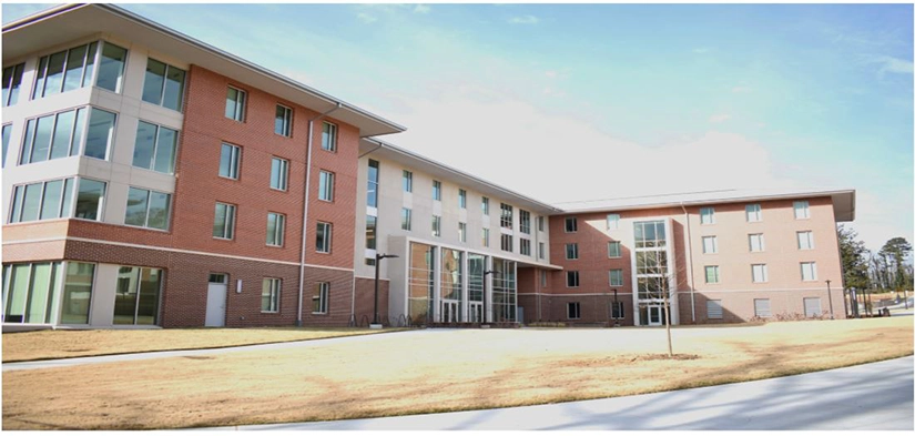 Modern college residence hall with large windows and a landscaped lawn.