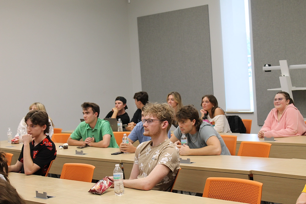 A classroom full of attentive students seated at desks, facing the front.
