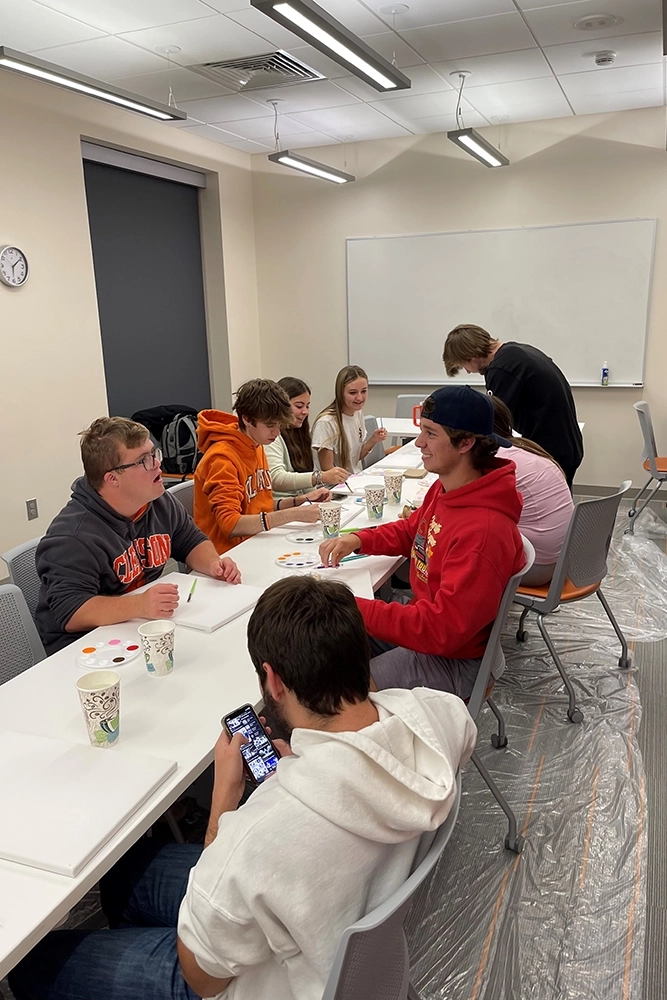 Students engaged in a painting activity during a group event in a classroom setting.
