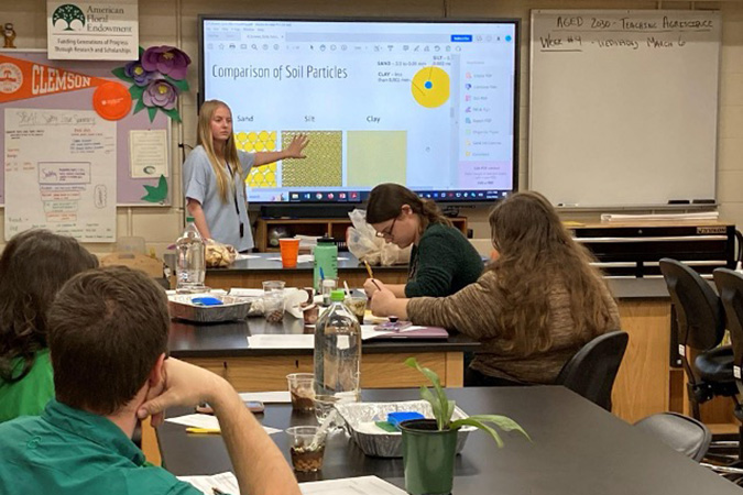 teacher teaching about soil particles to students in a classroom
