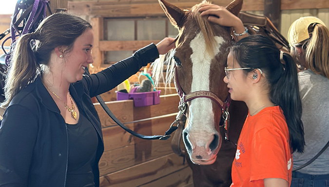 two students talking in a horse stable