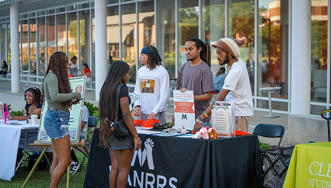 students at a stand talking to others about mannrs