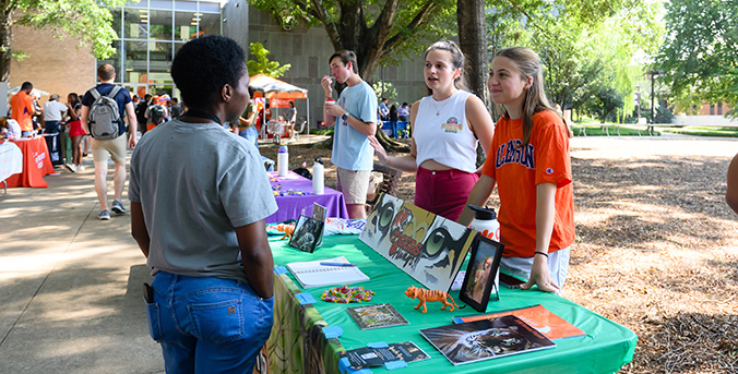 student speaking to others at a stand