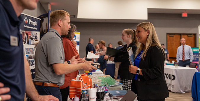 student speaking with employers at a career fair