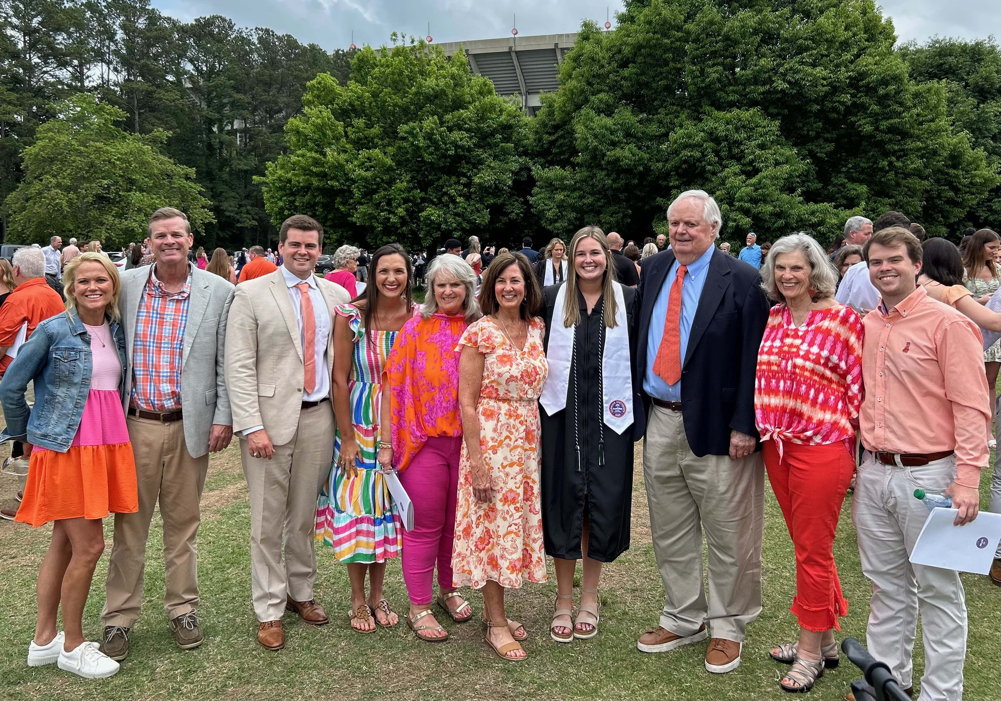 A group of people wearing formal clothes poses for photos on a lawn