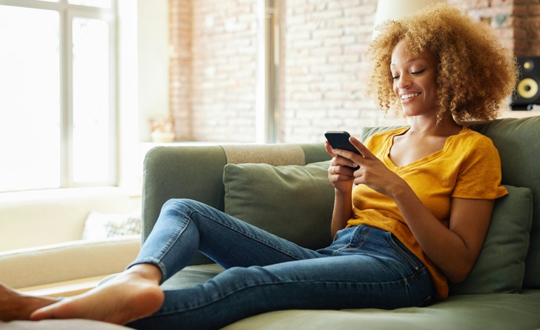 Person looking at a mobile phone laying on a couch