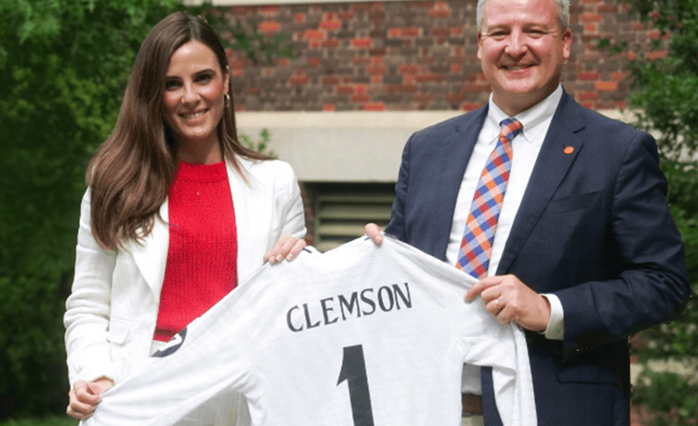 Two people holding up a clemson jersey