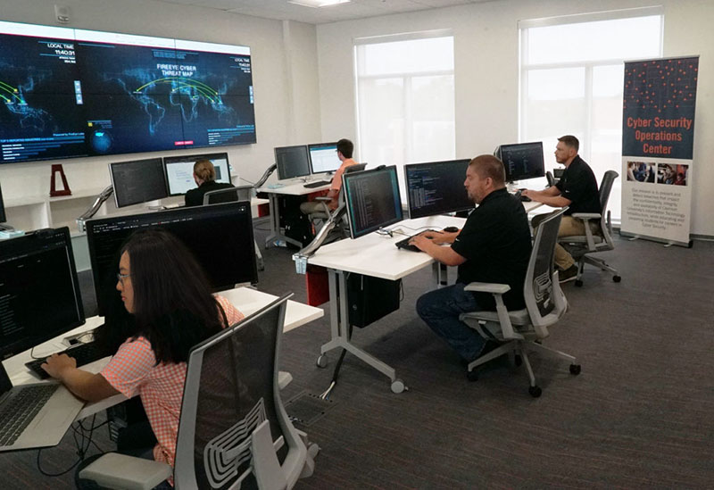 The Security Operations Center, with multiple desks with multiple monitors and student interns working.