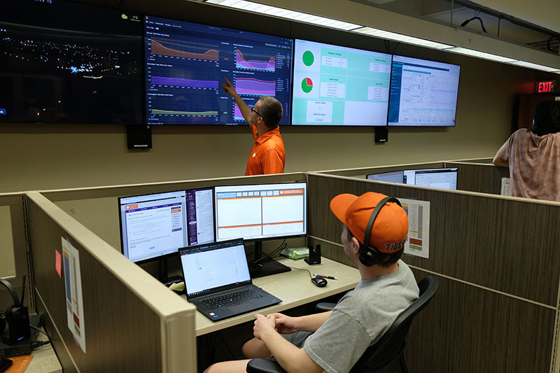 A support center employee showing a student worker information on a television screen.