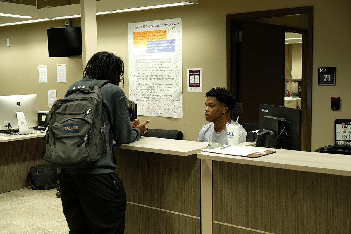 A Support Center student employee helps another student check in for help