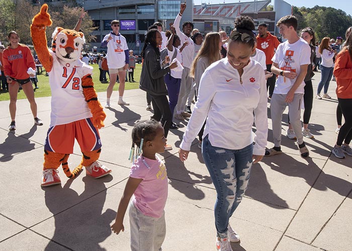 Mother and child hold hands at a Clemson athletics event