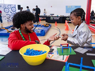 A volunteer and a child smile as they work together with blocks