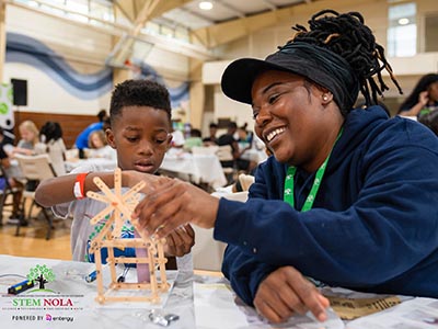 A volunteer helps a child with a popsicle stick project