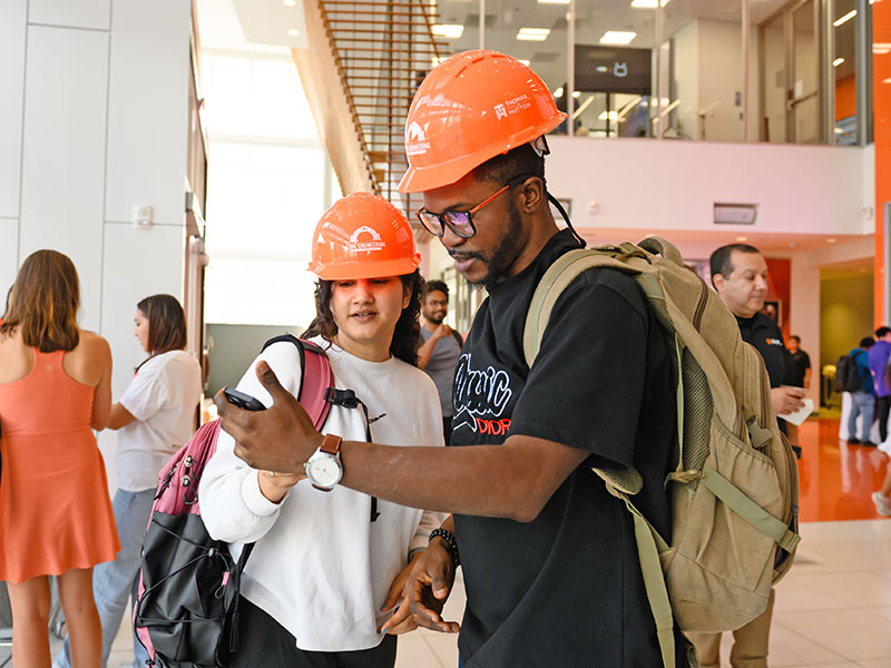 Two students at Hard hat Ceremony sharing images on phone.