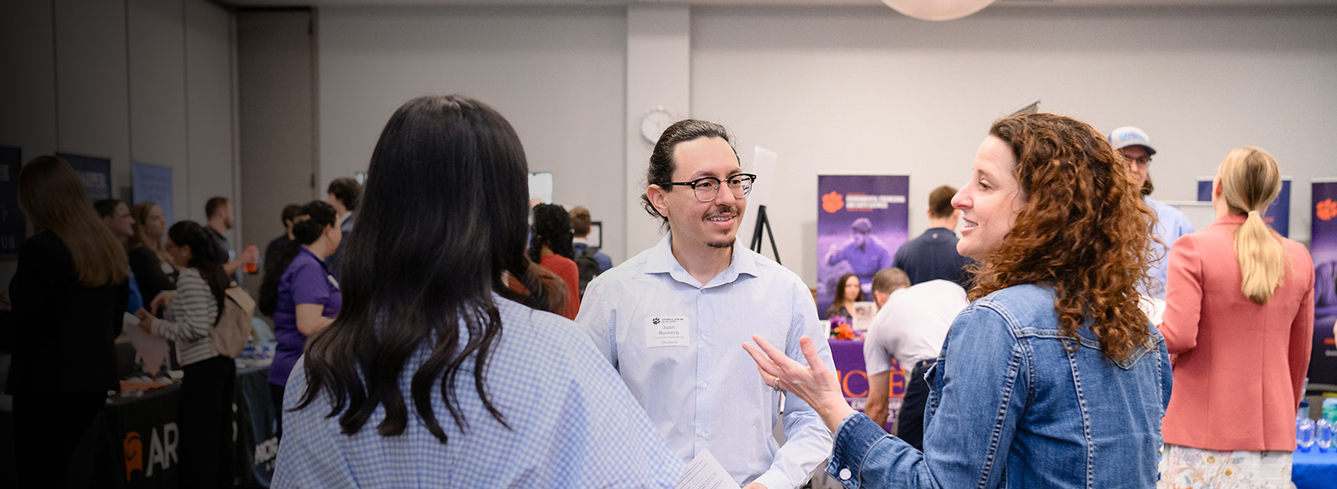 Career Fair event with student chatting with two industry representatives, while in the Hendrix Center