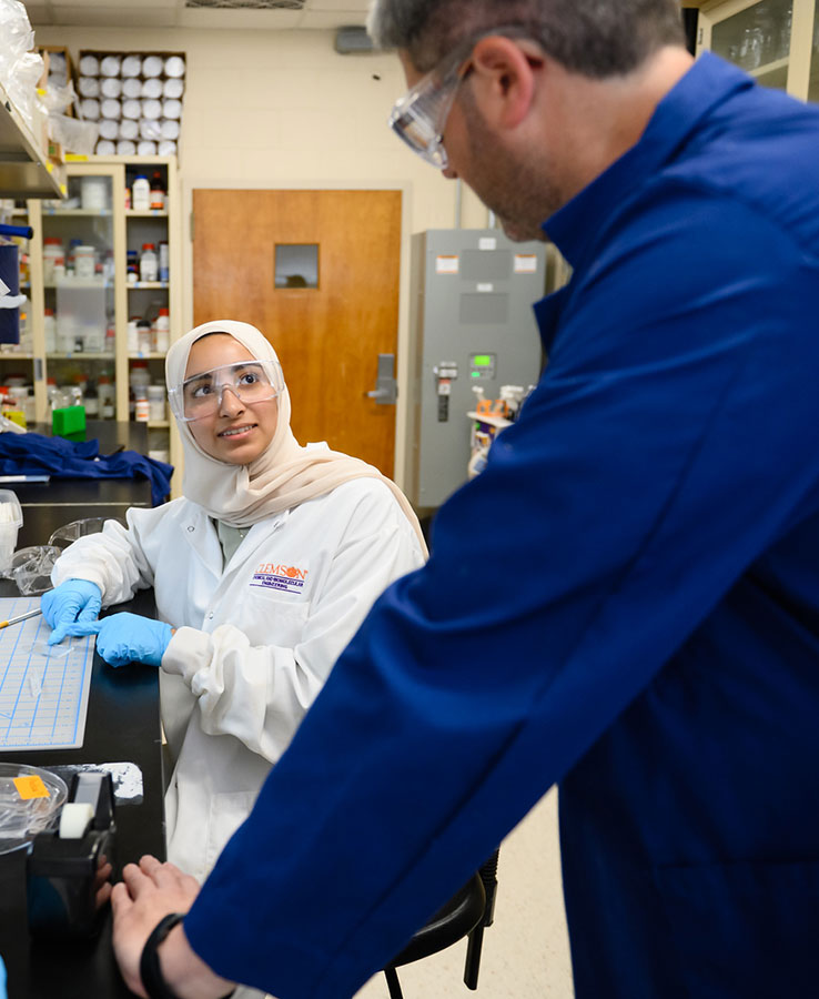 A student in the Eureka undergraduate summer program looks up towards Melvin in his research lab.