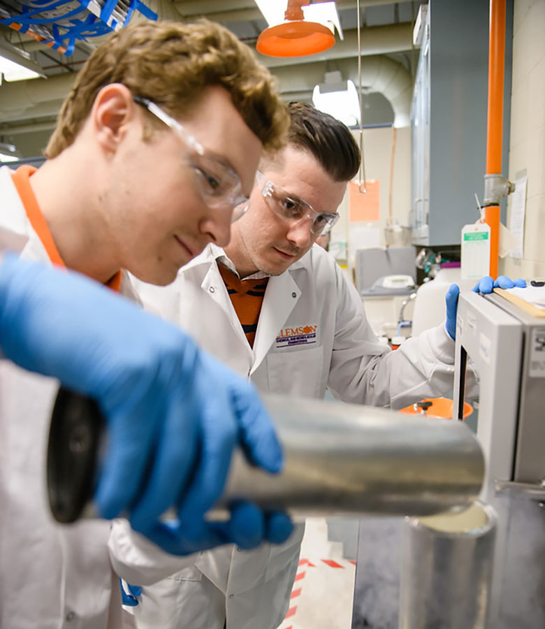 Davis observing as a student pours a liquid into cylinder.