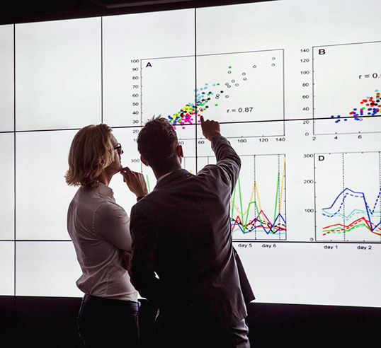 Two people looking at data on a large screen