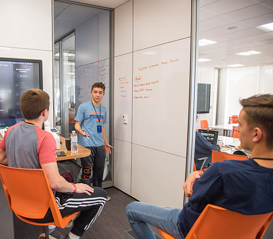 Students gathered at Watt Center writing on whiteboard